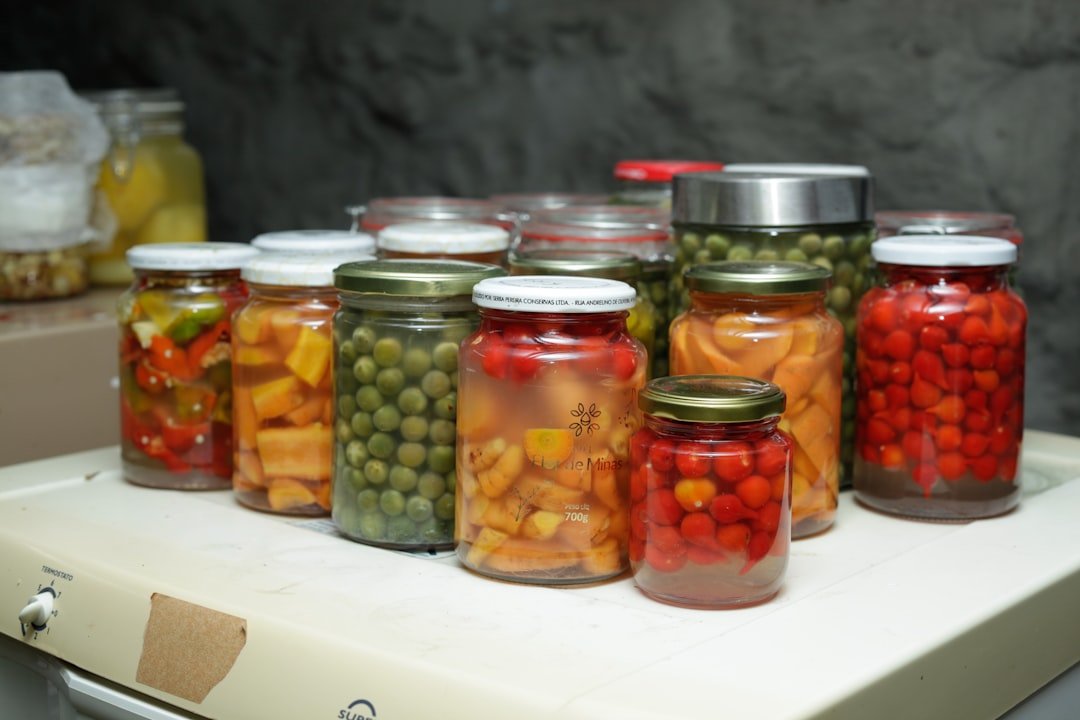 Glass jars filled with colorful fermenting vegetables including sauerkraut, pickles, and mixed vegetable ferments on a rustic wooden kitchen counter