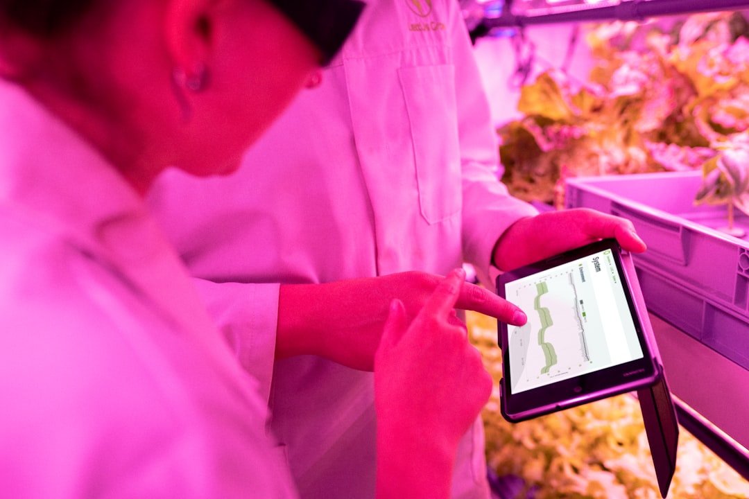 Young farmer using tablet technology in greenhouse to monitor plant health and growing conditions