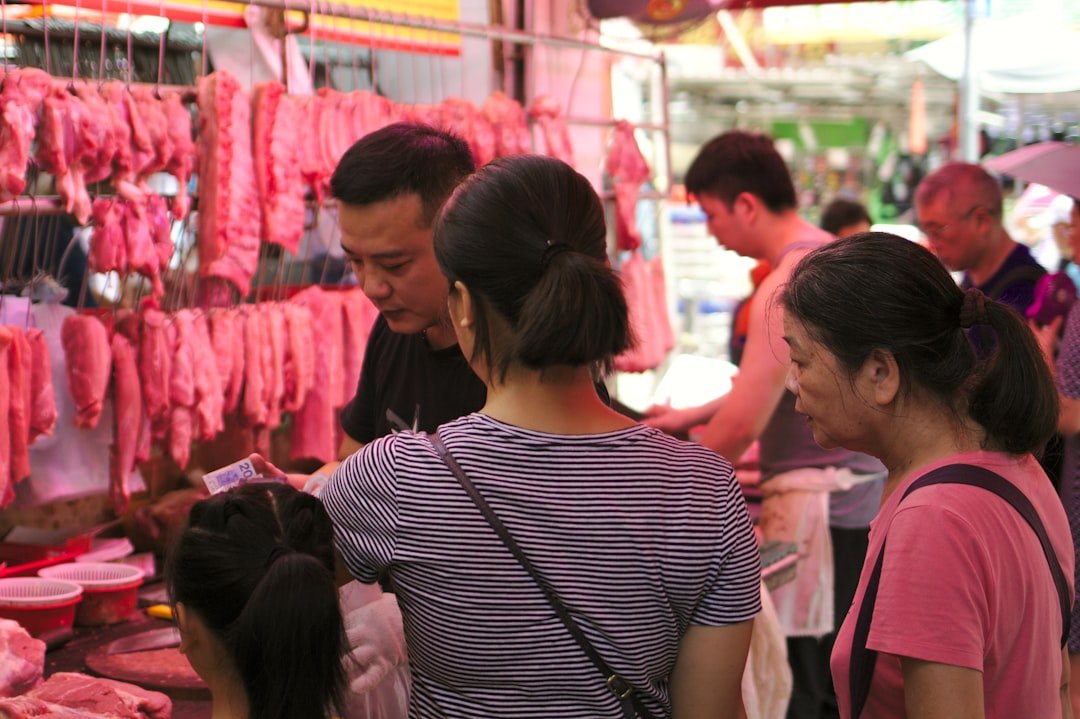 Vibrant farmers market scene with young farmer interacting with customers at produce stand displaying colorful organic vegetables